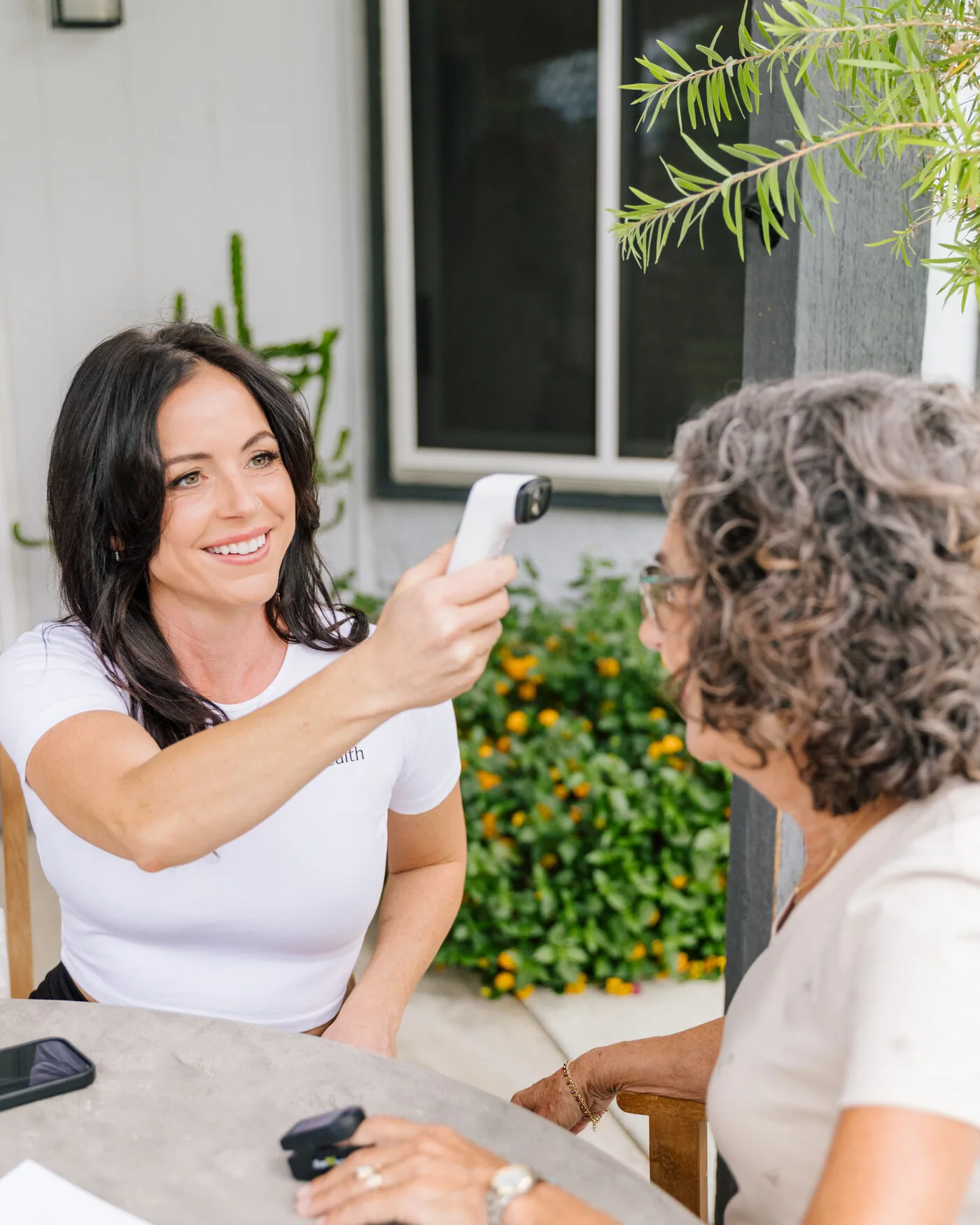 A Prata Health nurse taking an older client's temperature during a warm at-home visit