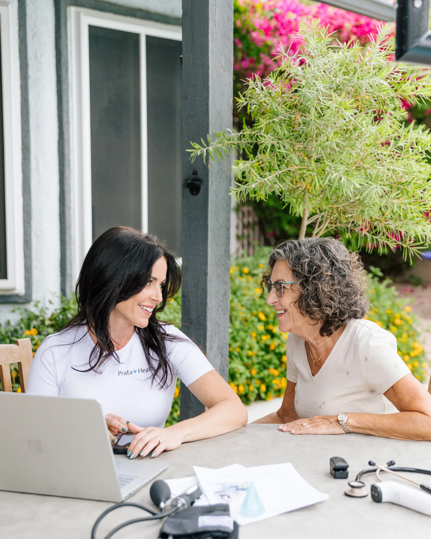 A Prata Health registered nurse reviewing readings with an older client at an outdoor table